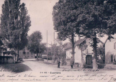 Photo ancienne du Village de Cuarnens, rue principale avec deux hommes qui discutent sous de grands arbres